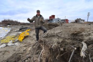 风暴工人站在岸边尤皮克人爱斯基摩Napakiak,阿拉斯加,永久冻土融化导致侵蚀和洪水。当地领导人正在考虑搬迁的村庄。