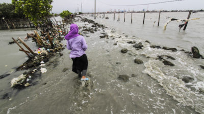 一名妇女在2018年2月在印度尼西亚中部爪哇省中央水平上升造成的破碎堤防。