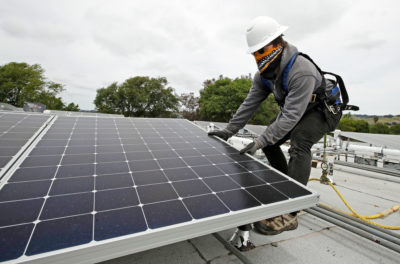 在冠状病毒爆发期间，一名工人在加州海沃德的一所房子上安装太阳能电池板。