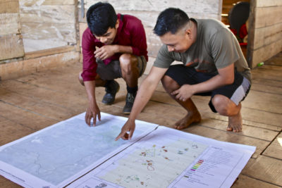 Wounaan森林技术人员审查了显示火灾和森林砍伐区域的地图。